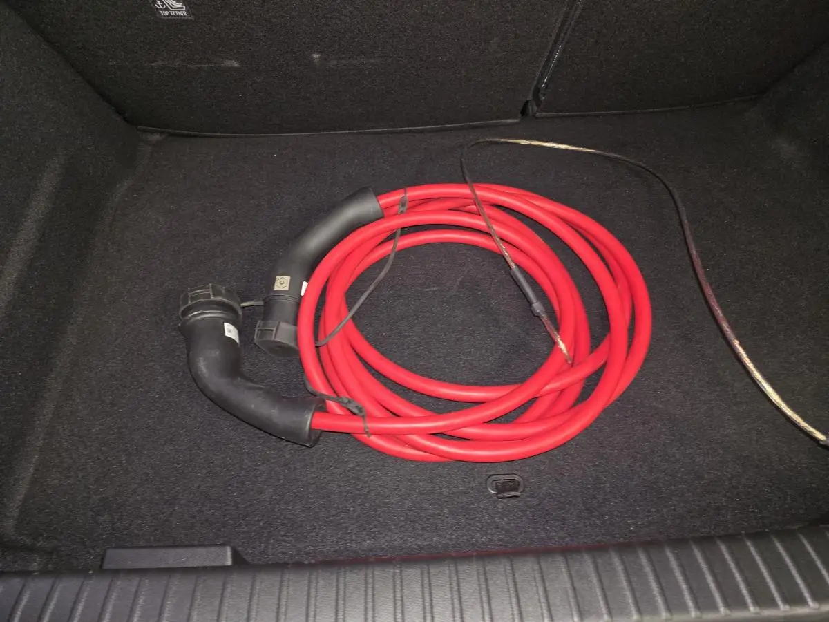 Câble de recharge rouge enroulé dans le coffre noir d'un Opel Mokka-e gris, vue intérieure arrière.