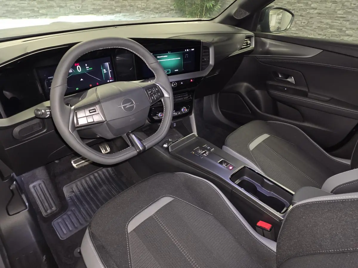 Vue intérieure avant droite de l’Opel Mokka-e 2025 gris, avec volant multifonction et écran tactile 10 pouces.