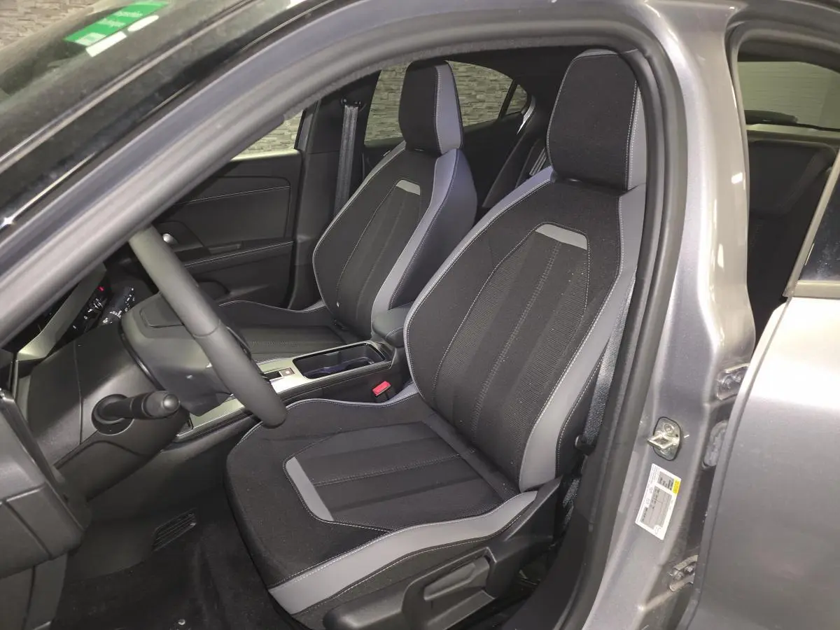 Vue intérieure côté conducteur de l'Opel Mokka-e gris 2025, sièges tissu noir et gris avec console centrale visible.