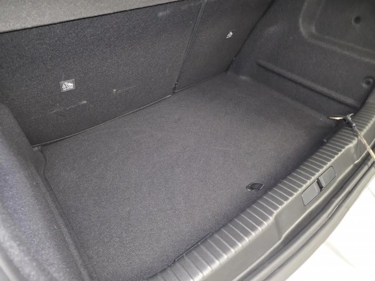 Coffre spacieux et propre de l’Opel Mokka-e gris, vue intérieure depuis l’ouverture arrière.