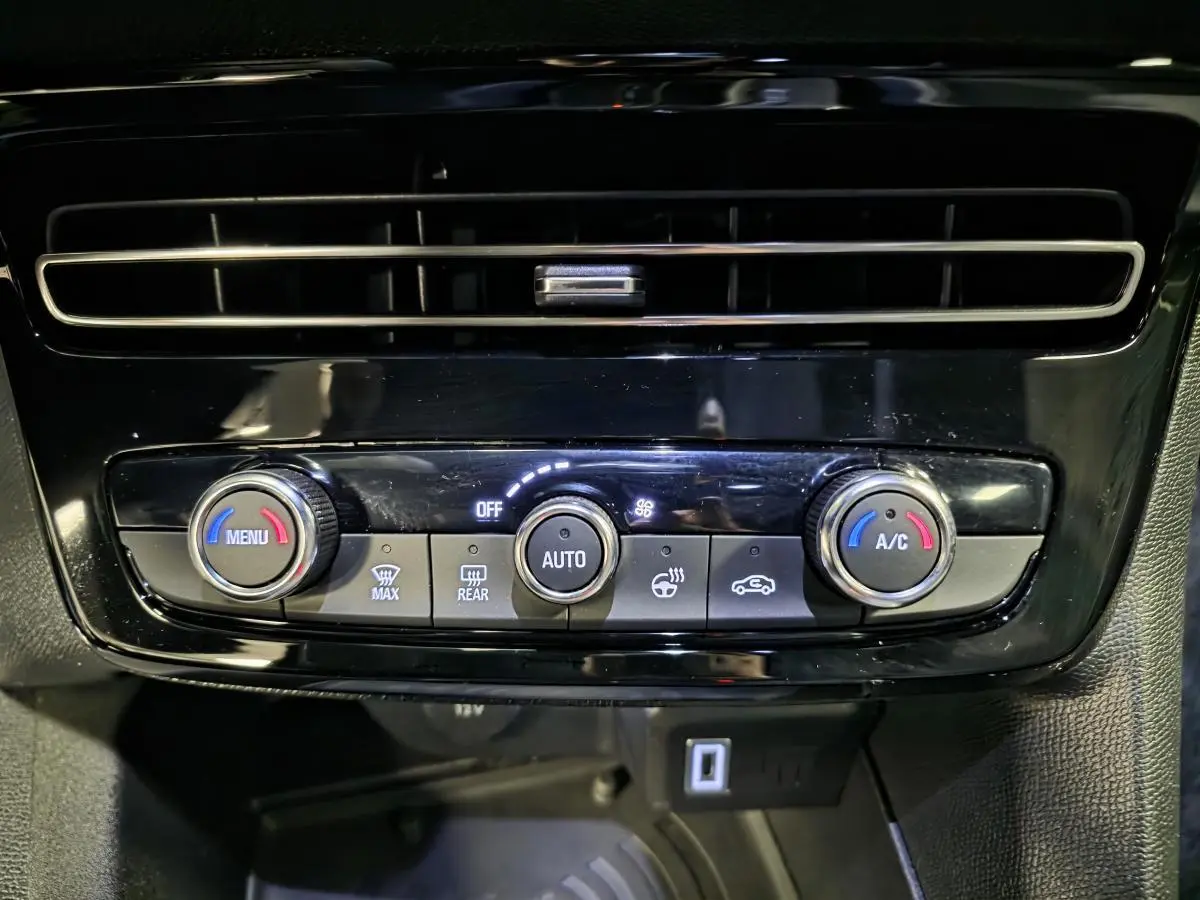 Détail de la console centrale noire avec commandes de climatisation automatique et ventilation du Opel Mokka-e gris.