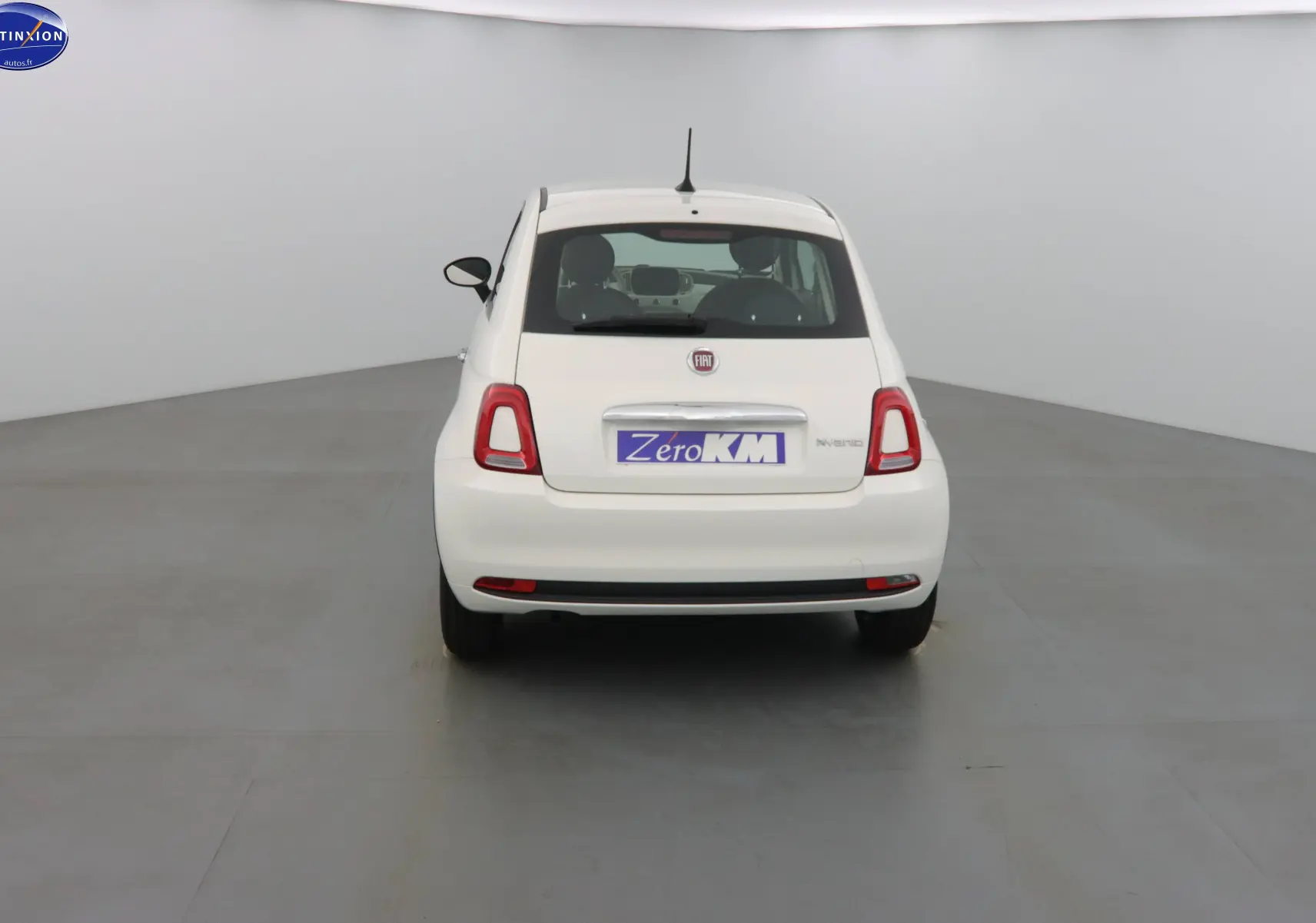 Vue arrière d'une FIAT 500 blanc gelato hybride 2023 avec feux arrière rouges et plaque Zero KM.