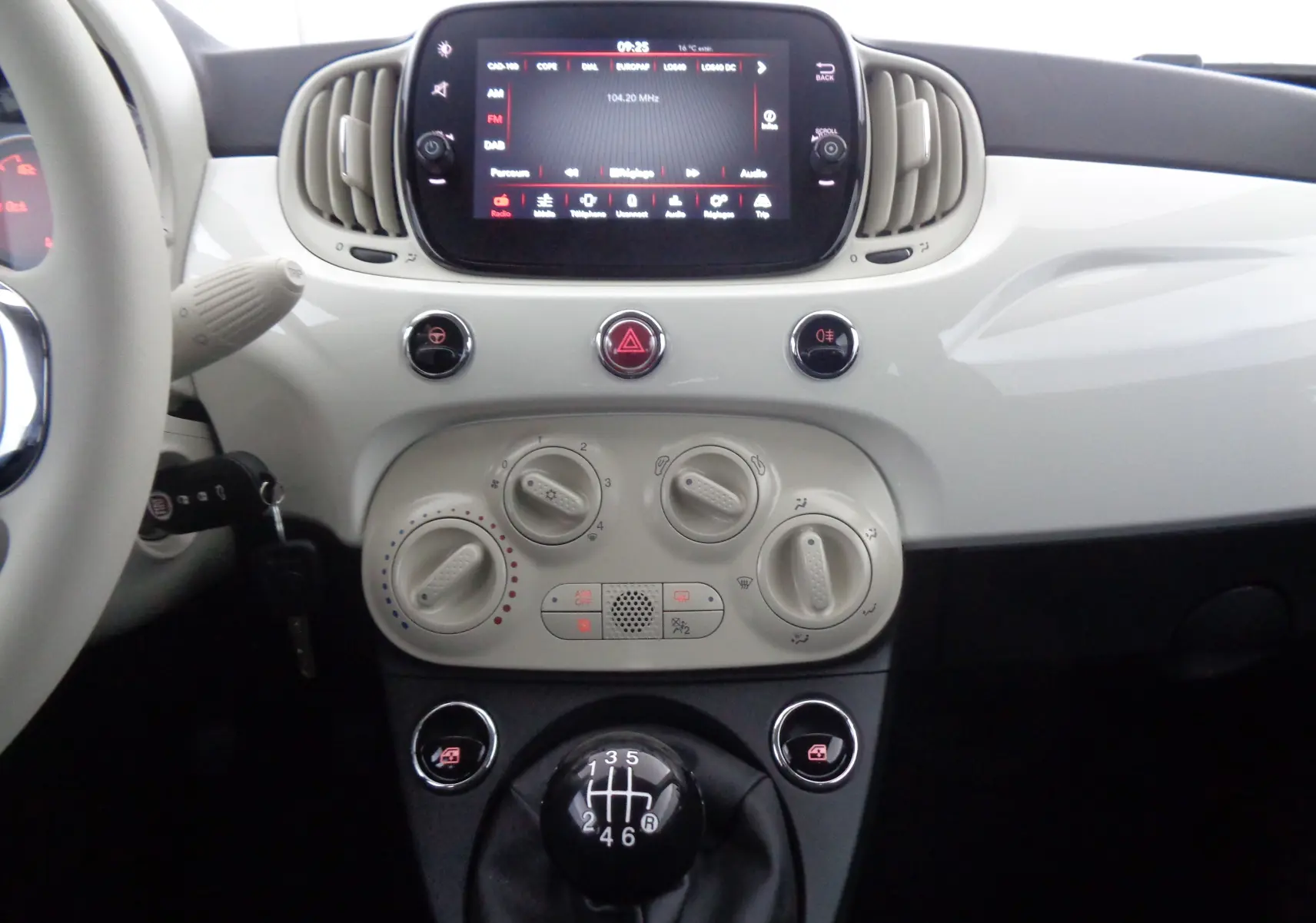 Tableau de bord blanc gelato de la Fiat 500 1.0 Hybrid 2023, vue centrale avec écran tactile et levier de vitesses manuel.