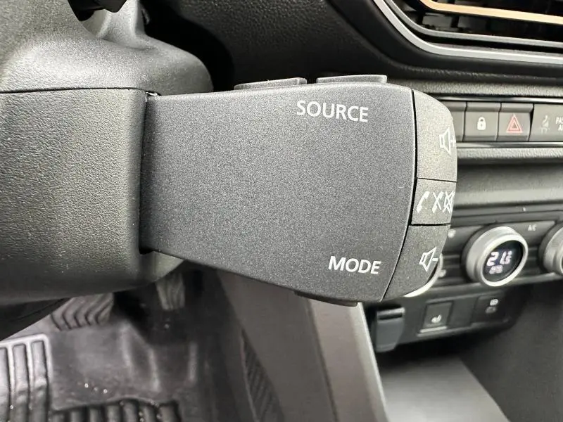 Gros plan sur la commande audio au volant du Dacia Jogger noir nacré 2025, avec boutons source et mode visibles.