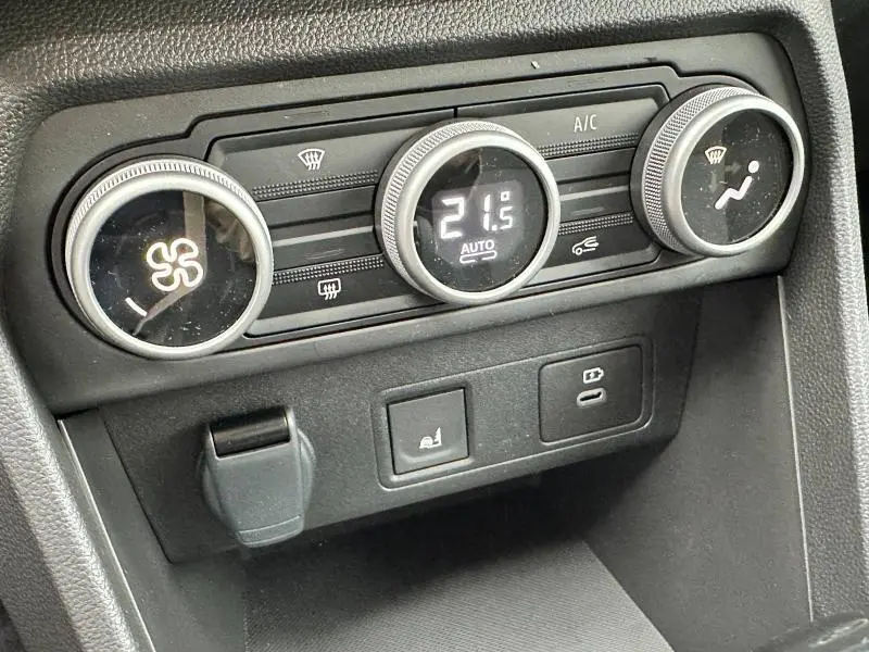 Gros plan sur les commandes de climatisation automatique du Dacia Jogger 1.6 hybrid noir nacré, affichant 21,5°C.
