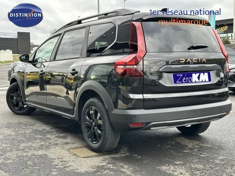 Vue 3/4 arrière droite du Dacia Jogger 2025 noir nacré métallisé avec barres de toit et jantes noires.