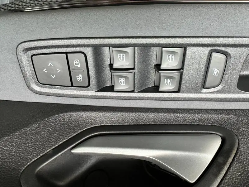 Gros plan sur les commandes de lève-vitres et la poignée intérieure côté conducteur du Dacia Jogger noir nacré.