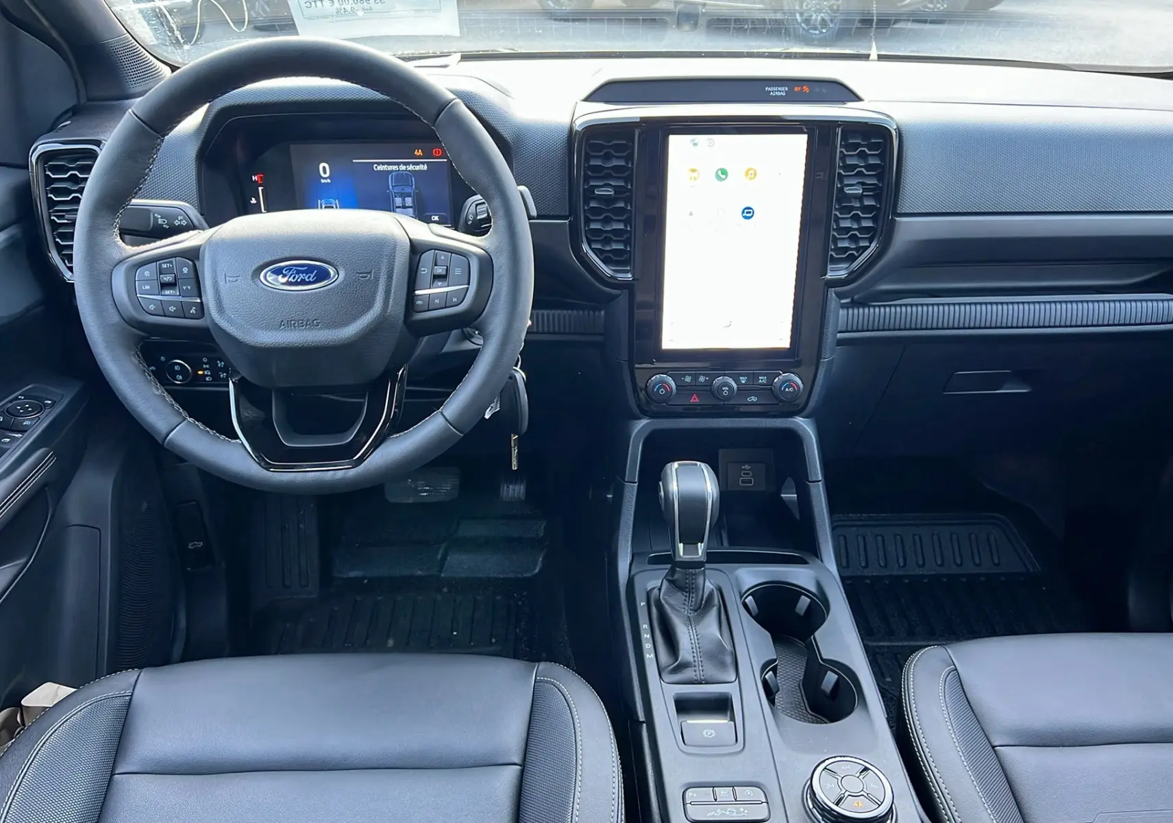 Vue intérieure frontale du Ford Ranger 2025 noir shadow, avec volant multifonction, écran tactile vertical et levier de boîte automatique.