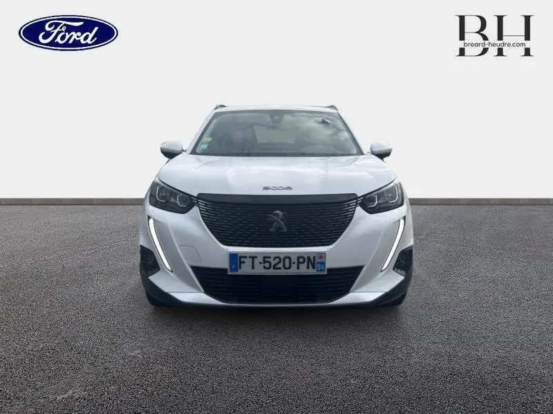 Vue de face du Peugeot 2008 blanc banquise avec calandre noire et feux LED verticaux allumés.