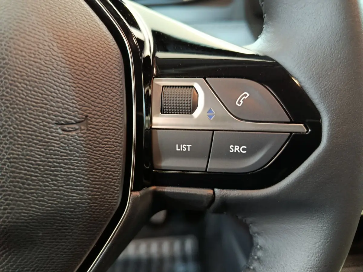 Gros plan sur les commandes multifonctions à droite du volant en cuir noir du Peugeot 208 PureTech 100 S&S Allure.