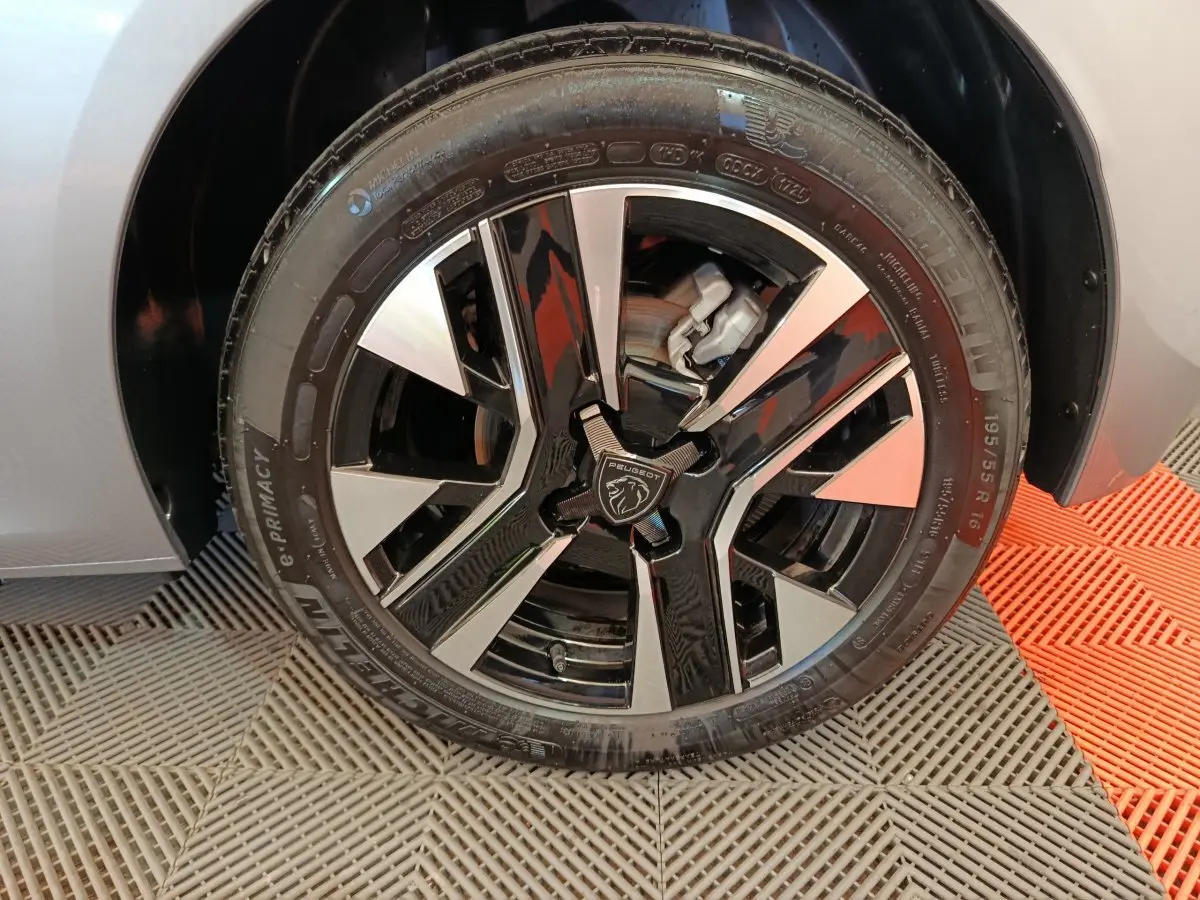 Gros plan sur la roue avant droite gris clair de la Peugeot 208 PureTech 100 S&S Allure avec jante alliage bicolore.