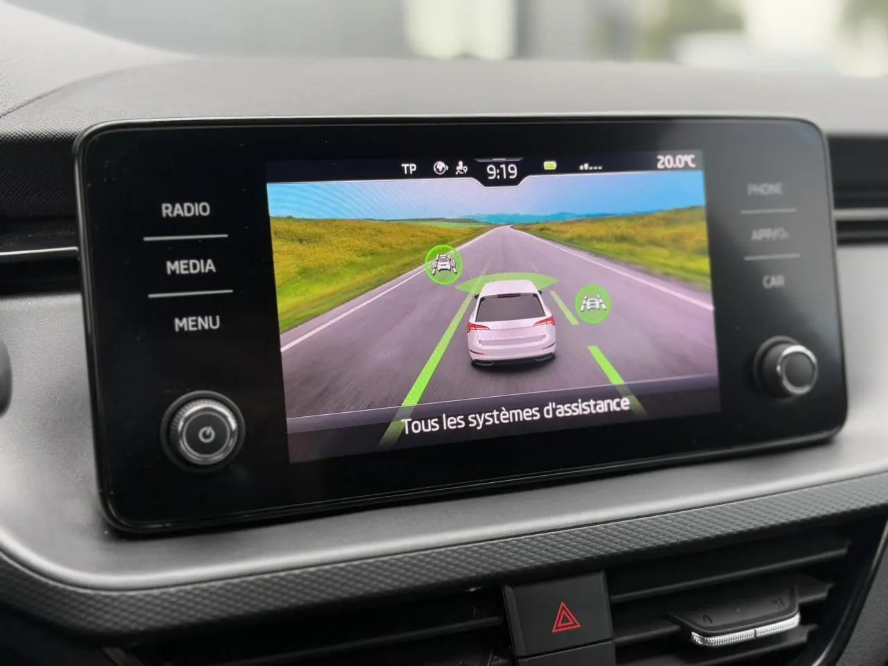 Écran tactile central de la Skoda Scala TSI 110 DSG Ambition montrant l'assistance à la conduite sur fond de route.