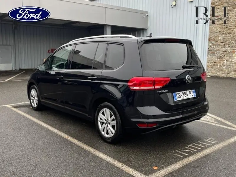 Volkswagen Touran noir intense nacré vu de trois quarts arrière droit, avec vitres teintées et jantes alu.