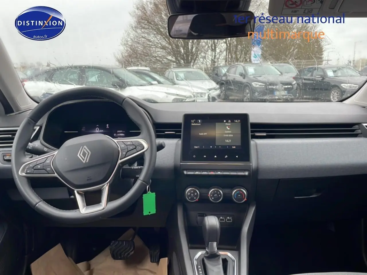 Vue intérieure avant de la Renault Clio V blanche, montrant le volant multifonction et l’écran tactile central.