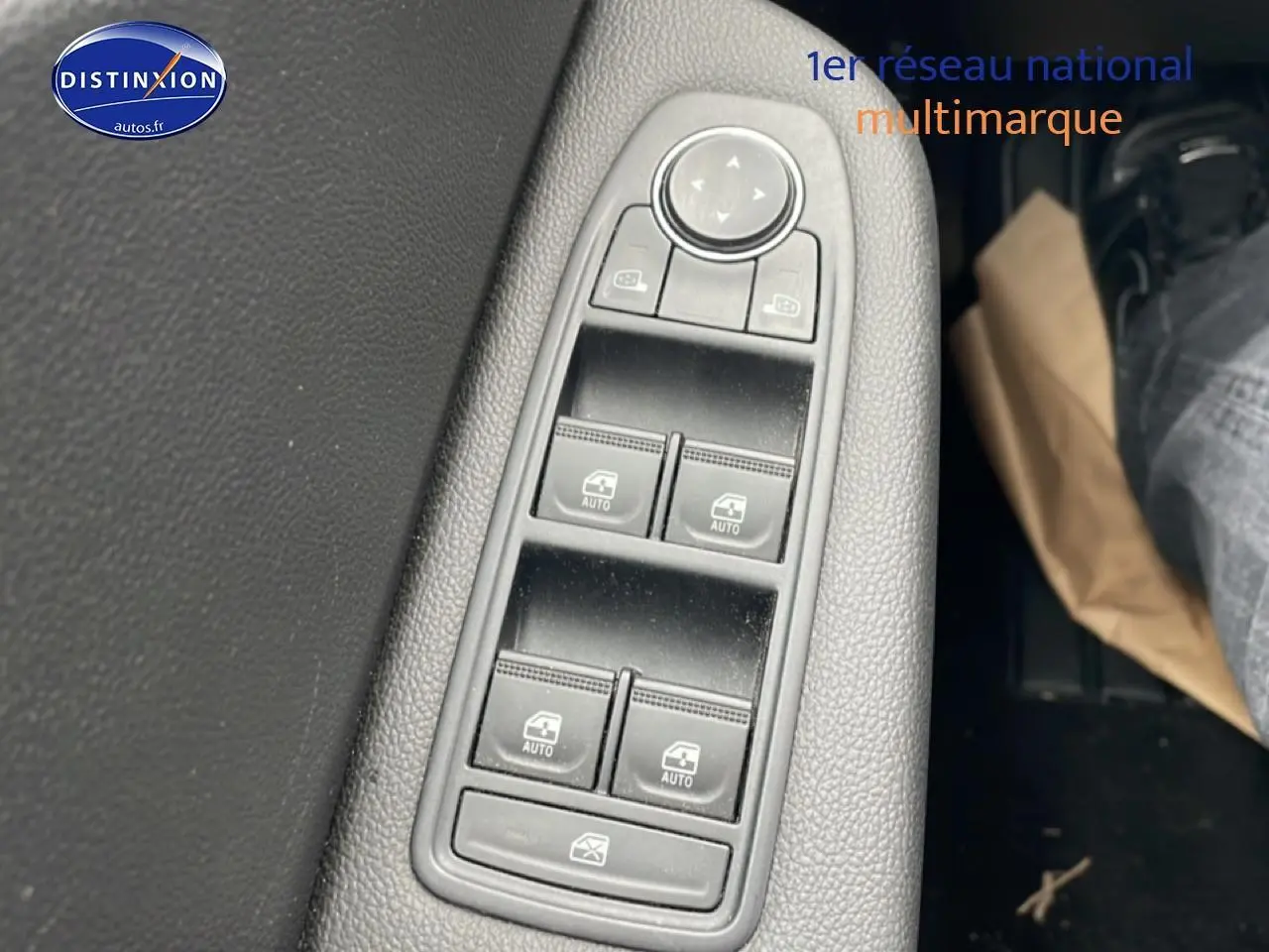 Gros plan sur les commandes des vitres électriques côté conducteur de la Renault Clio V blanche, avec réglage des rétroviseurs.