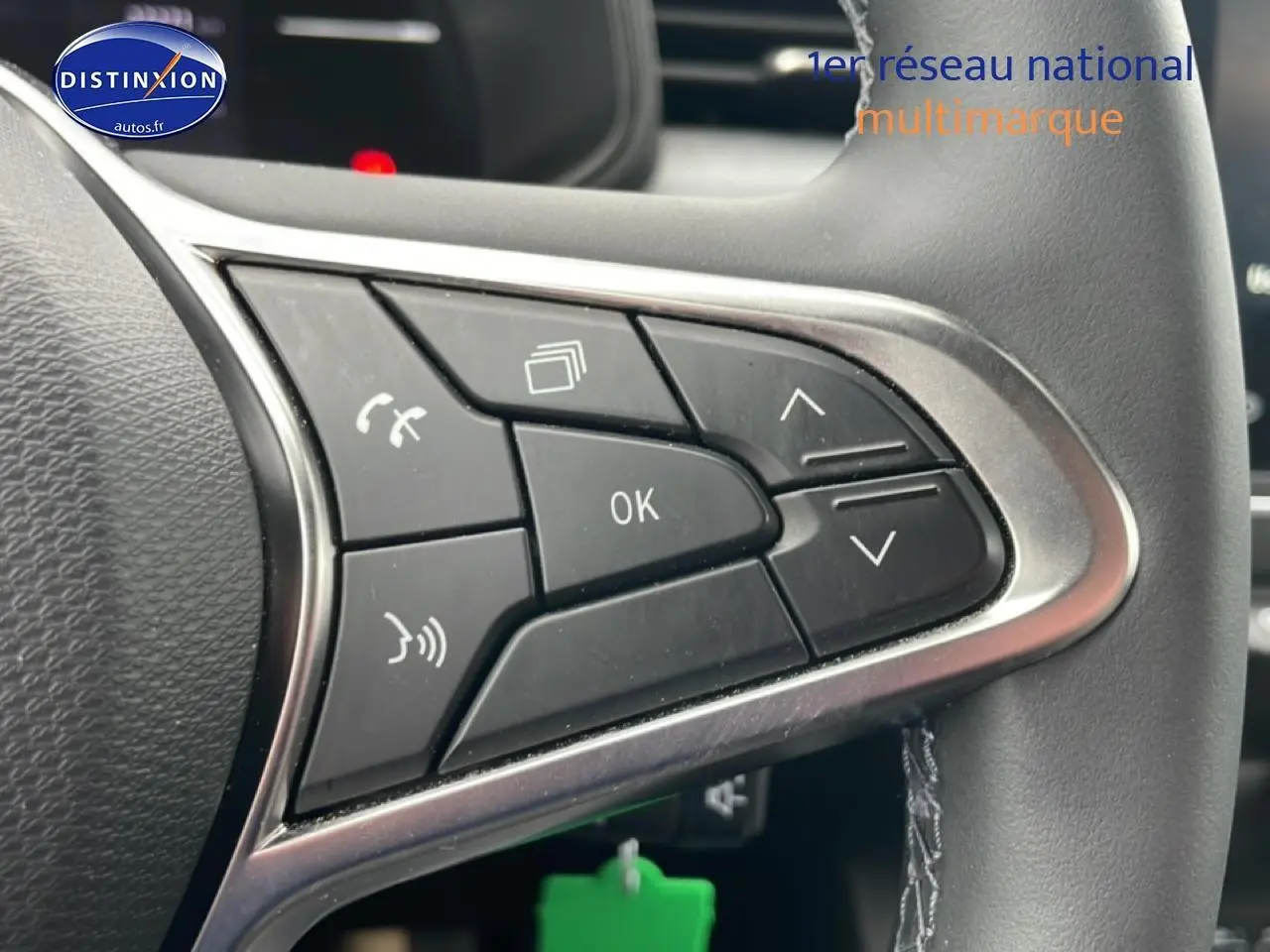 Gros plan sur les commandes multifonctions noires du volant de la Renault Clio V blanche, avec contour argenté.