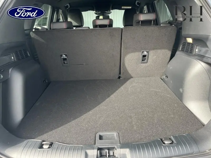Coffre spacieux du Ford Kuga gris Solar, vue intérieure arrière avec banquette rabattue et finitions noires.