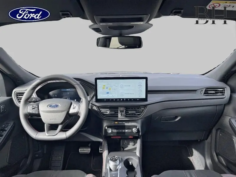 Vue intérieure avant du Ford Kuga 2026, tableau de bord moderne avec écran tactile central et volant multifonction noir.