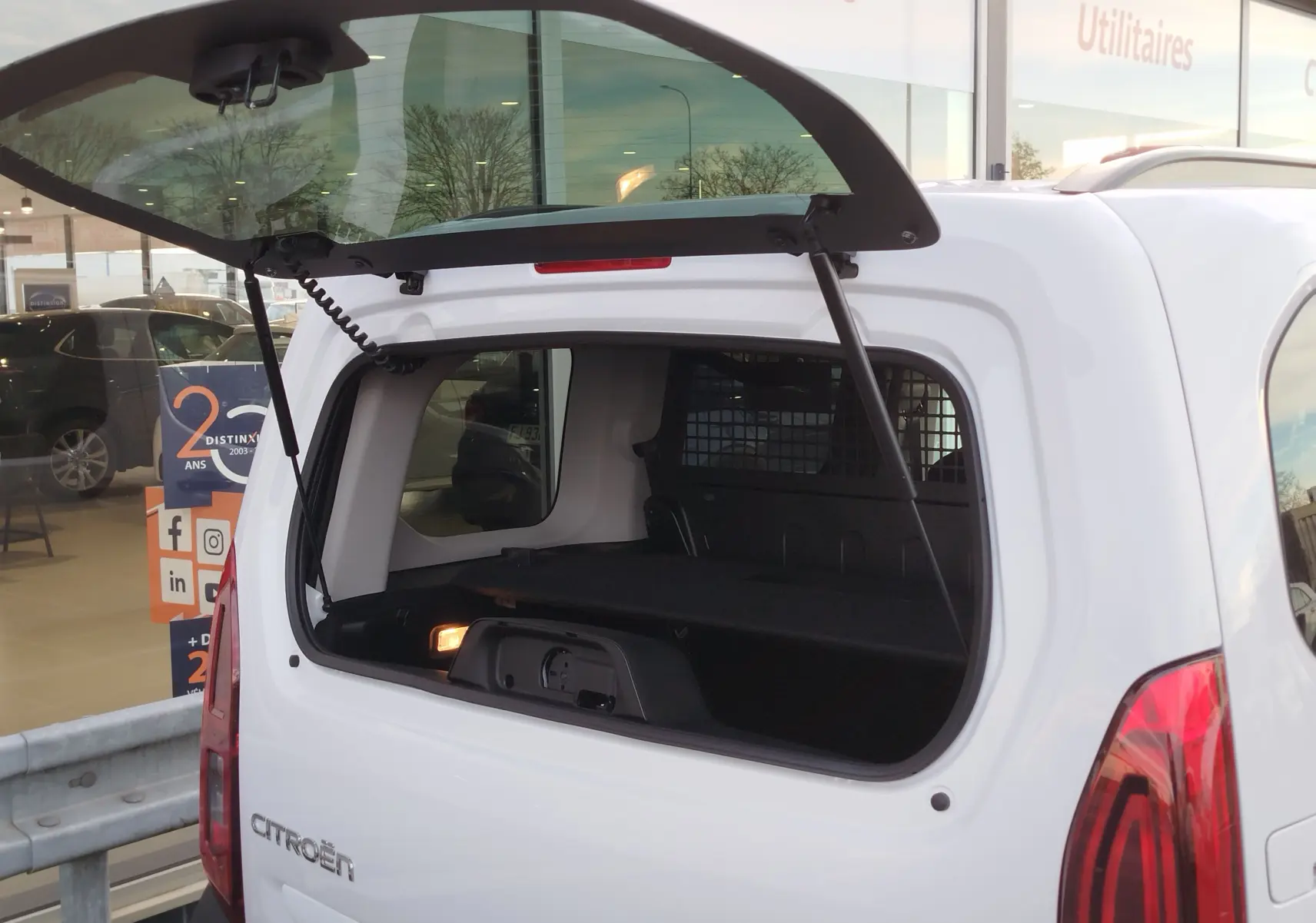 Vue arrière du Citroën Berlingo Kaolin White 2025 avec hayon ouvert, montrant l’espace de chargement et la grille de séparation.