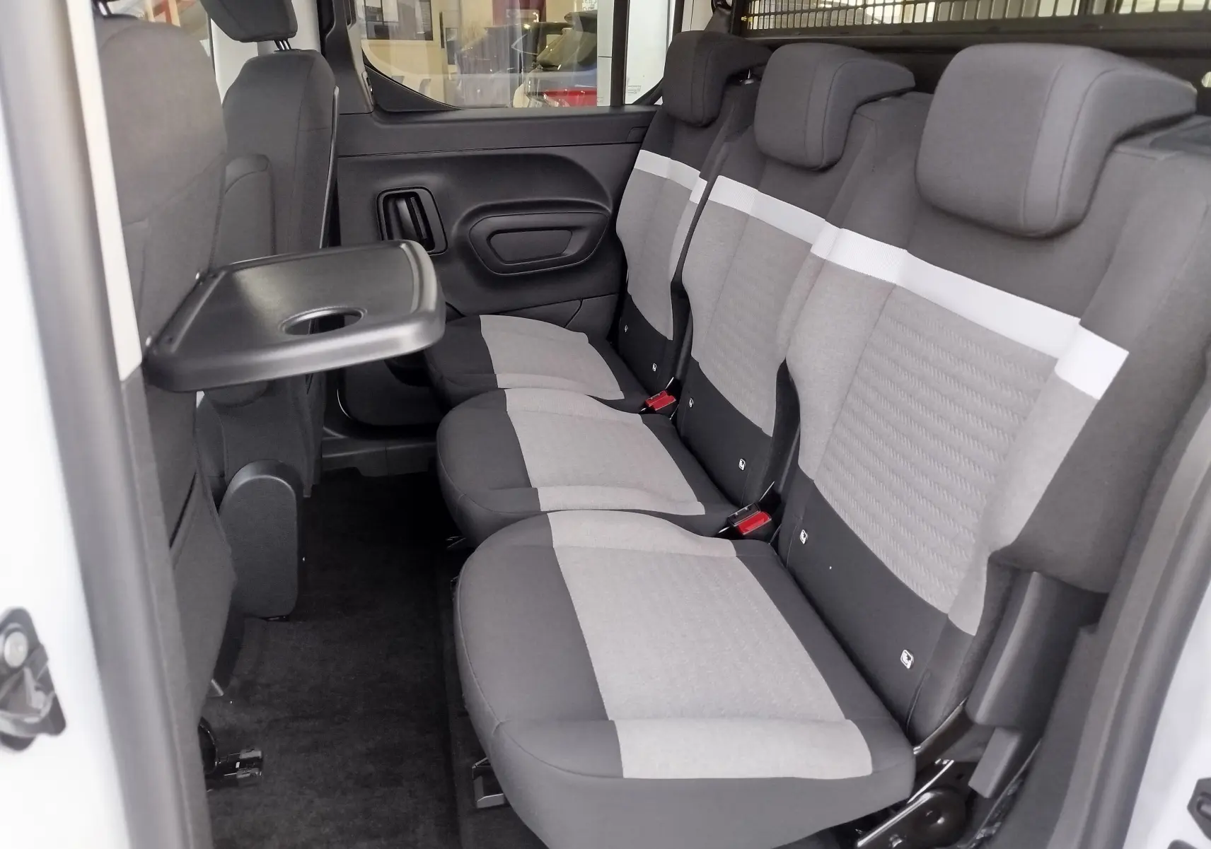 Vue intérieure côté droit du Citroën Berlingo 2025 Kaolin White, montrant la banquette arrière 3 places avec tablette rabattable.