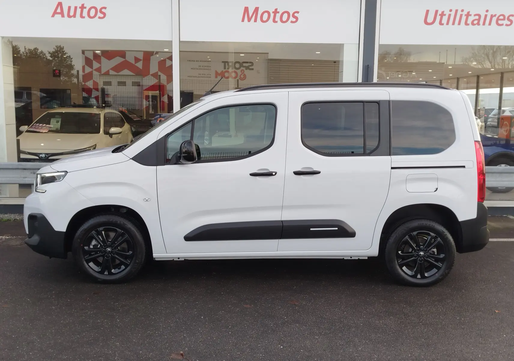 Vue de profil côté gauche du Citroën Berlingo Kaolin White 2025 avec jantes noires et protections latérales noires.