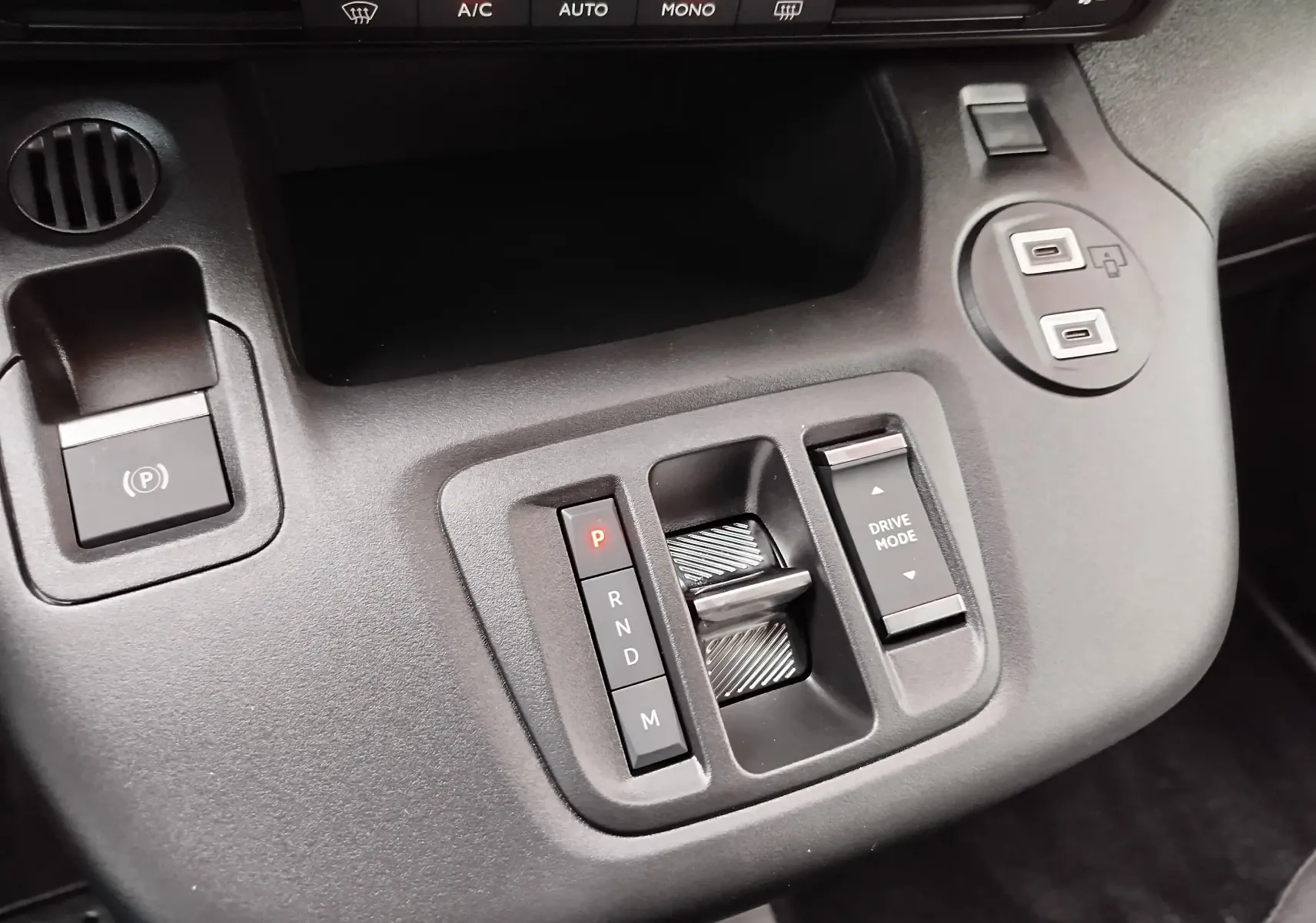 Vue rapprochée de la console centrale noire du Citroën Berlingo 2025 avec commande de boîte auto et boutons Drive Mode.