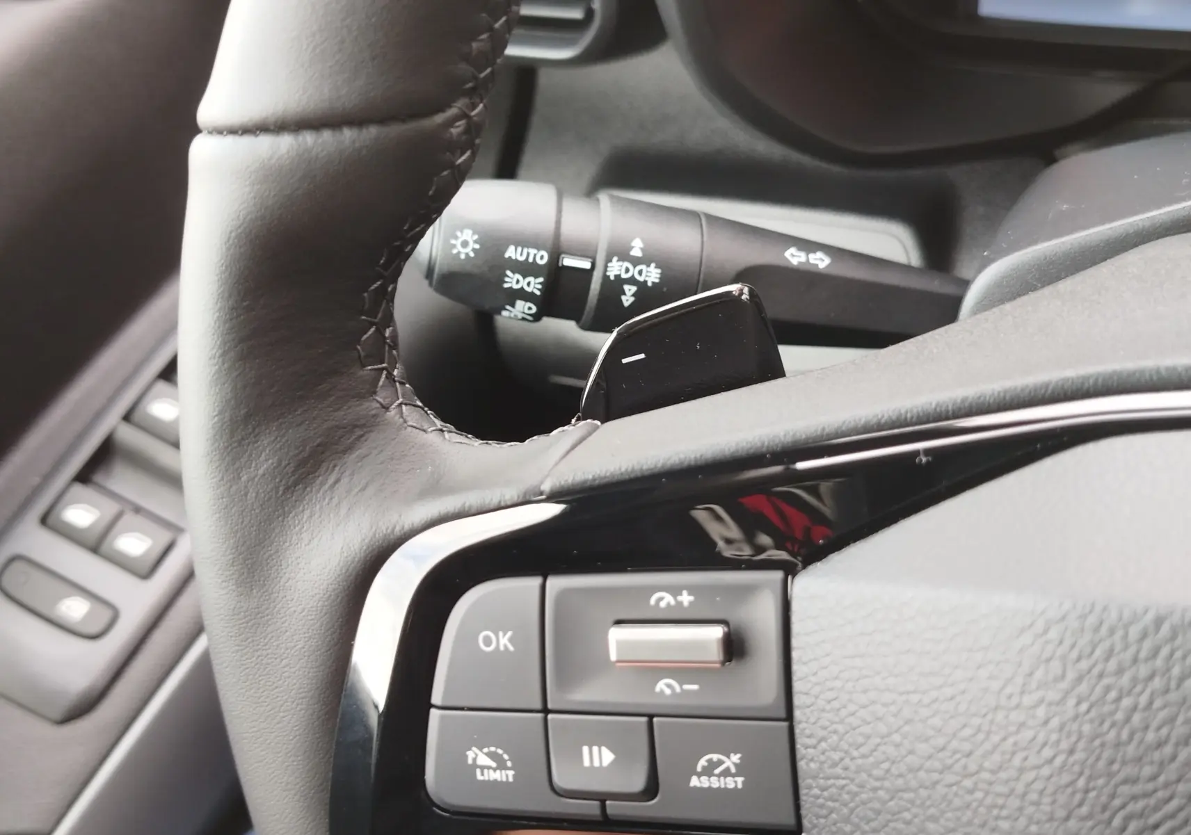 Gros plan sur le côté gauche du volant en cuir noir du Citroën Berlingo 2025, avec commandes intégrées et levier de clignotant visible.