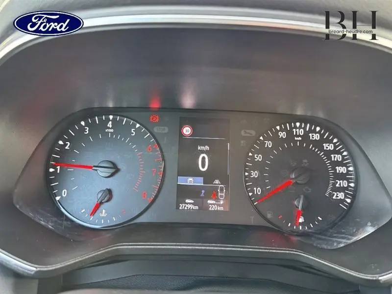 Tableau de bord de Renault Clio blanc, affichage digital au centre avec compteur vitesse et compte-tours visibles.