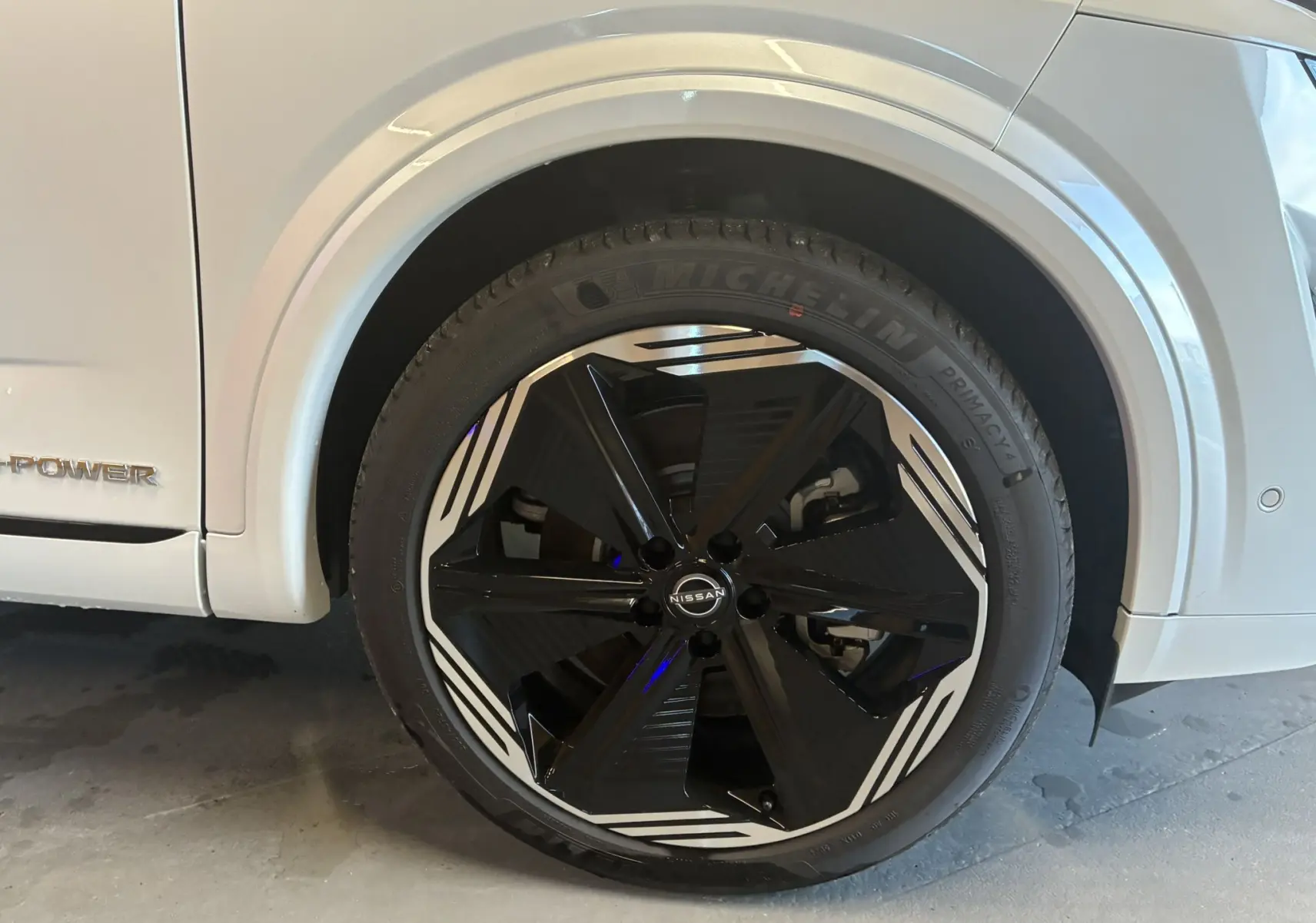 Gros plan sur la roue avant gauche du Nissan Qashqai blanc nacré, jante noire et blanche au design moderne.