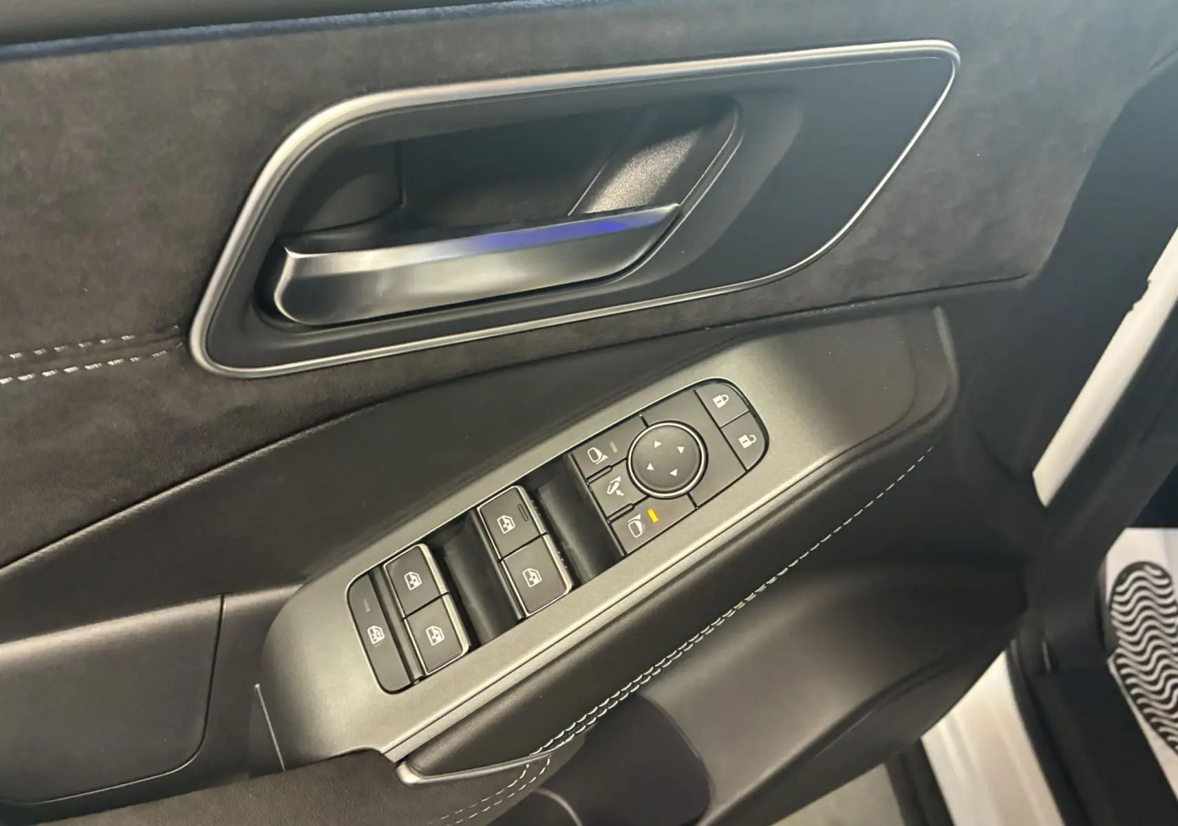 Gros plan sur la porte côté conducteur du Nissan Qashqai blanc nacré 2025, avec commandes électriques et poignée noire.