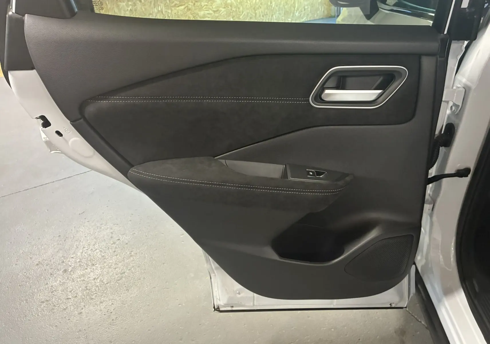 Gros plan sur la porte arrière droite du Nissan Qashqai blanc nacré, avec garniture noire et surpiqûres contrastantes.