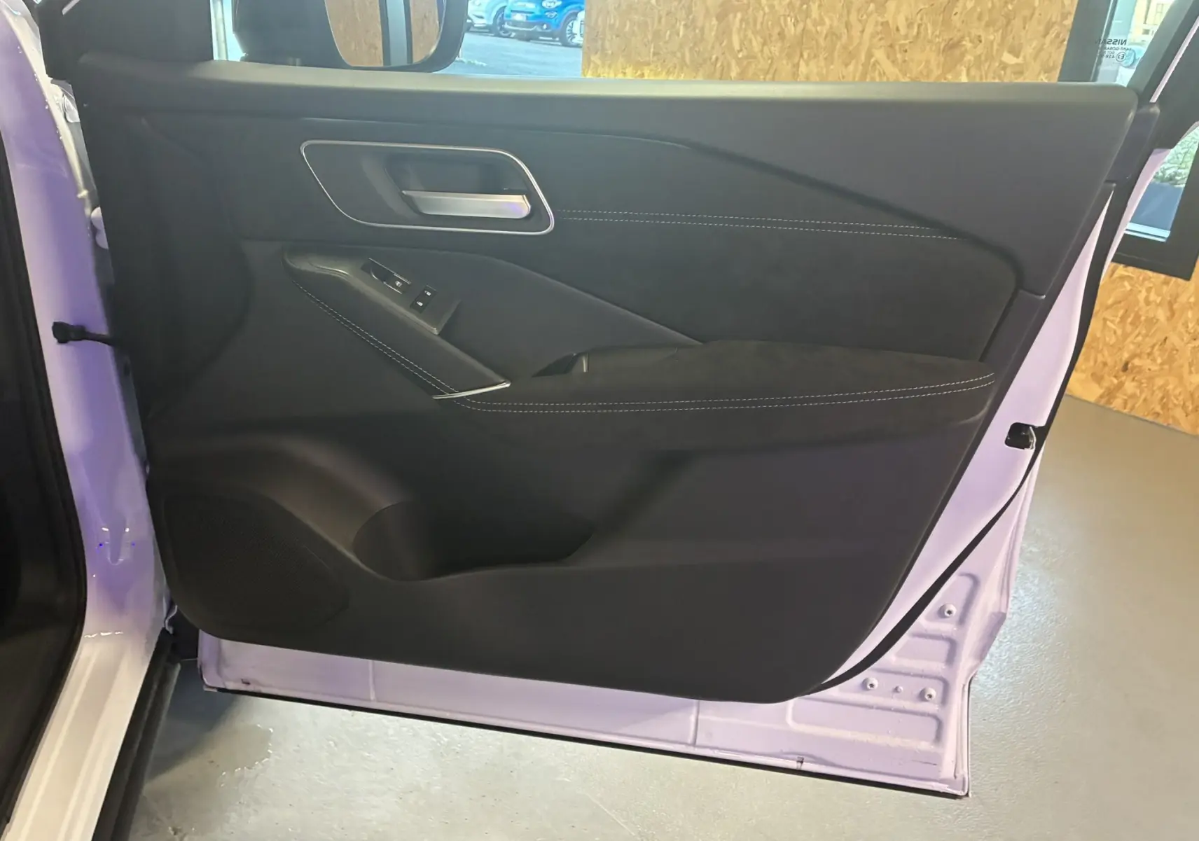 Vue intérieure de la porte côté gauche du Nissan Qashqai blanc nacré avec garniture noire et surpiqûres blanches.