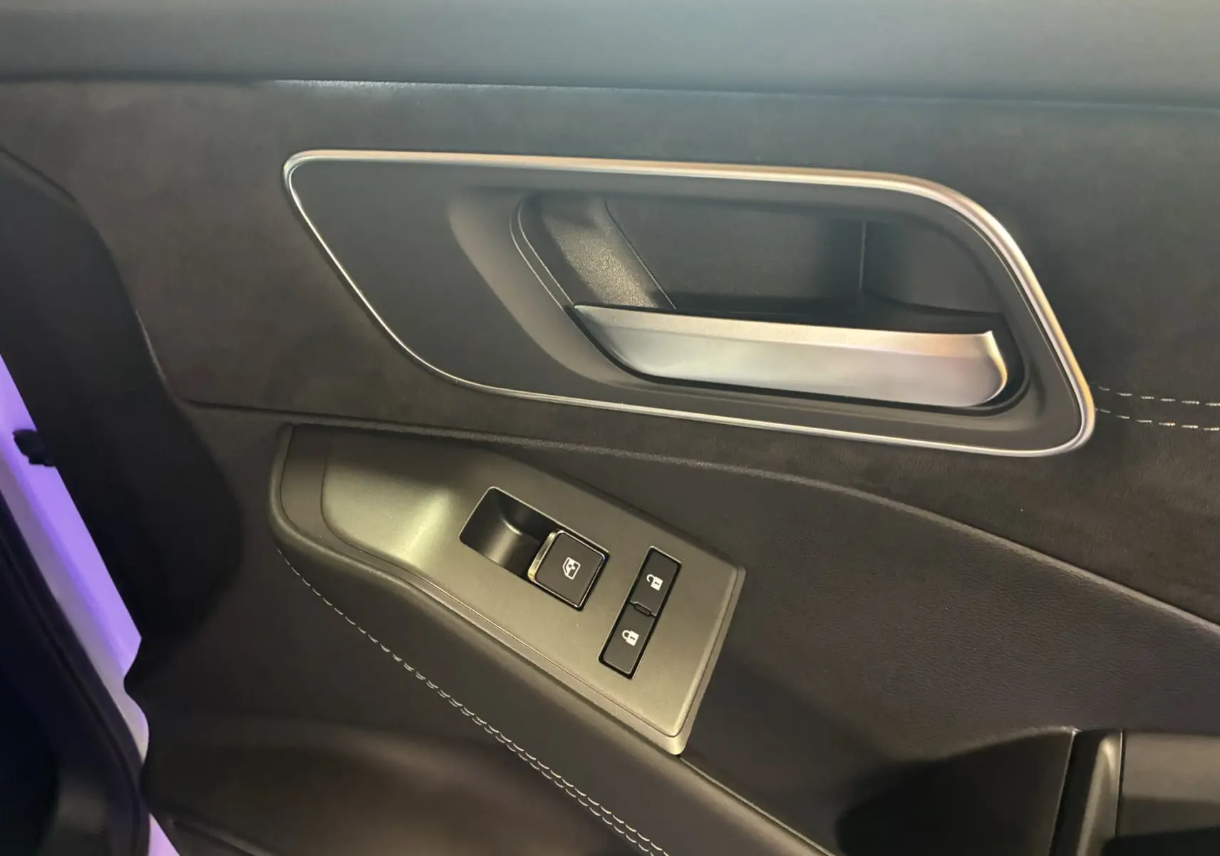 Gros plan sur la poignée intérieure côté gauche du Nissan Qashqai 2025, garniture noire avec surpiqûres blanches.