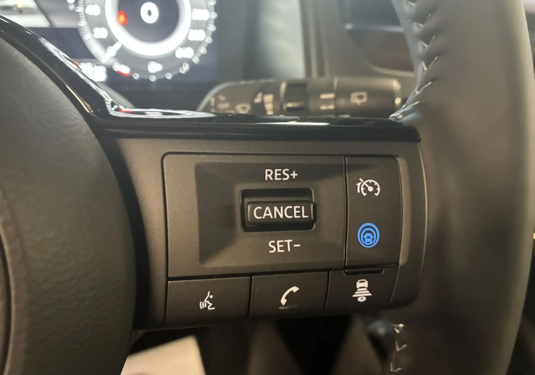 Gros plan sur les commandes de régulateur de vitesse au volant noir du Nissan Qashqai 2025 blanc nacré.