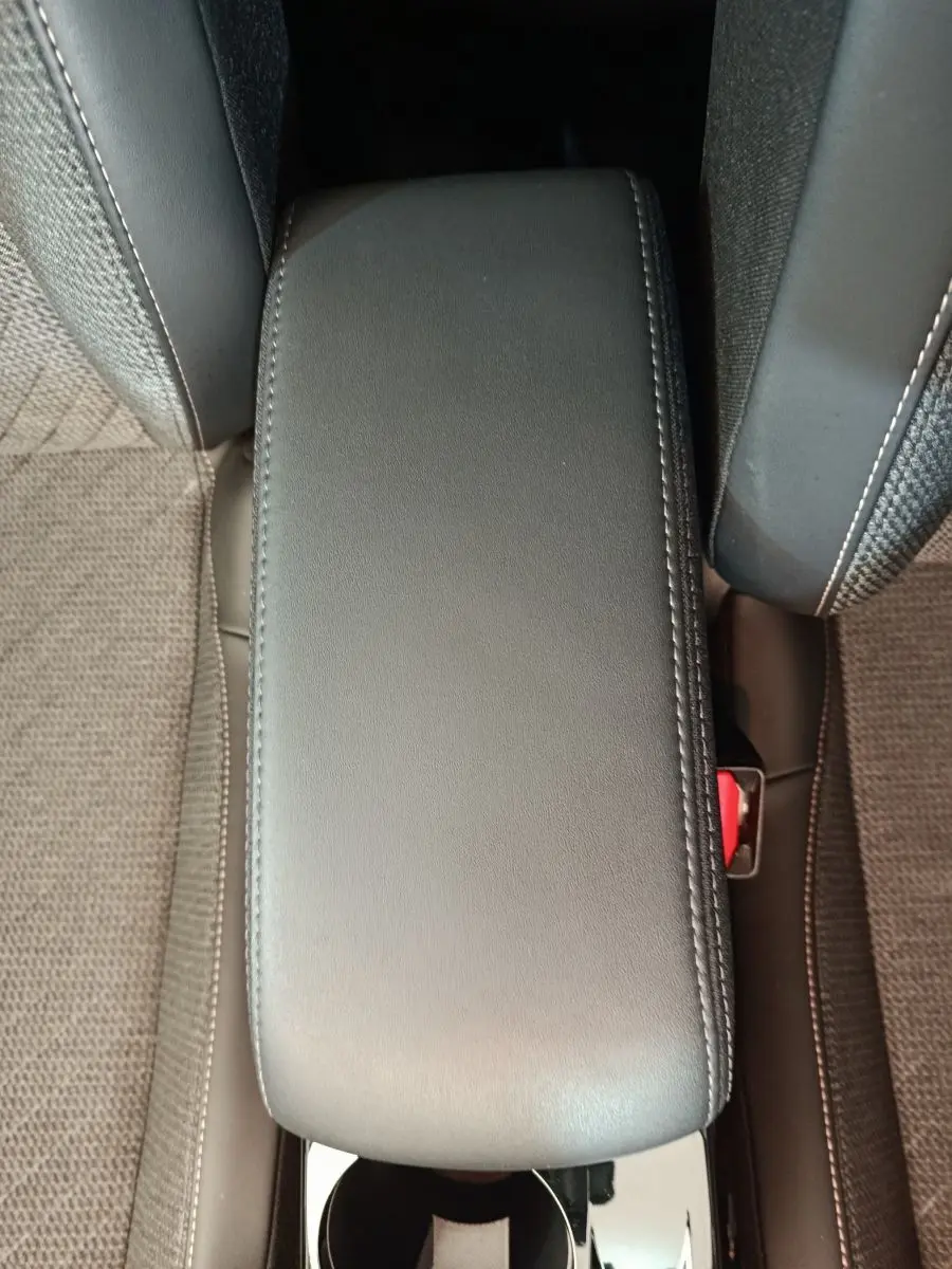 Vue plongeante sur l'accoudoir central en cuir noir entre les sièges tissu gris foncé d'une Peugeot 208 2025.