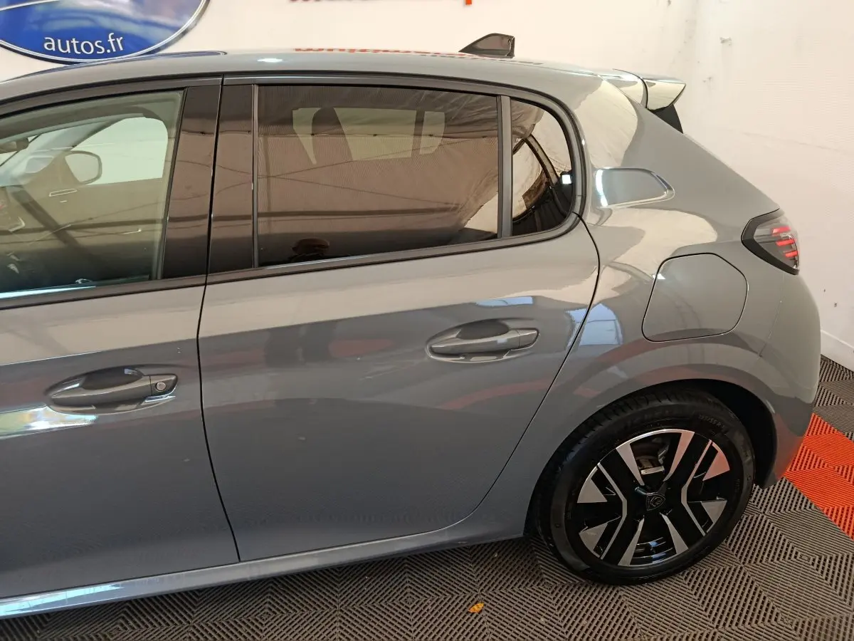 Vue latérale droite d'une Peugeot 208 gris foncé avec jante alliage au design moderne et rétroviseur ton caisse.