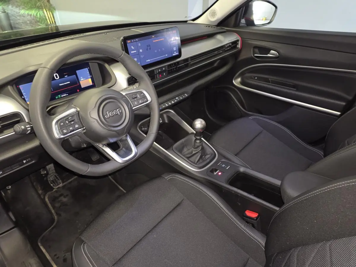 Vue intérieure côté conducteur du Jeep Avenger noir 2025, mettant en valeur le volant multifonction et la console centrale avec boîte manuelle.