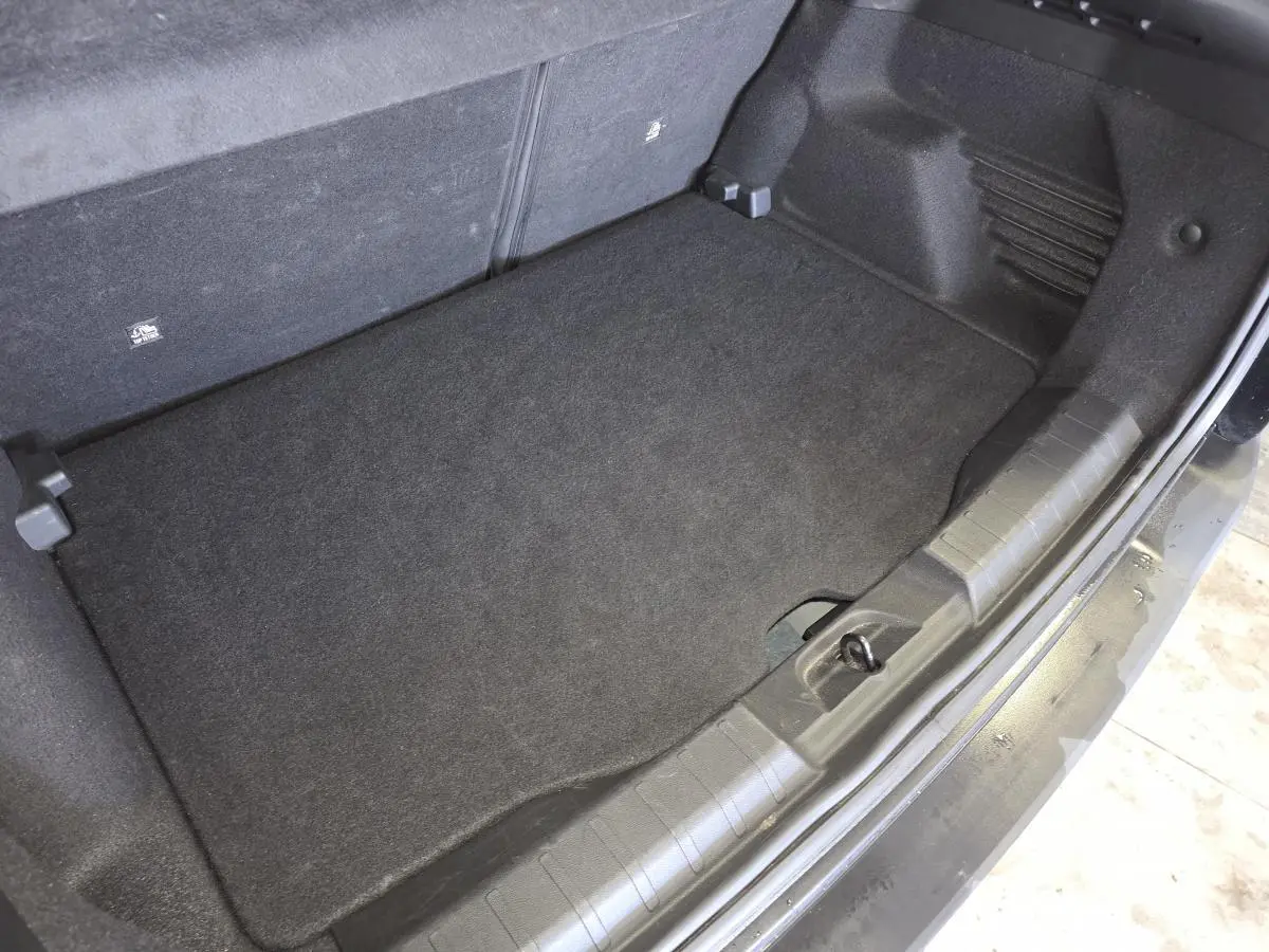 Vue plongeante sur le coffre noir du Jeep Avenger 2025, montrant le plancher de coffre modulable et tapis de sol.