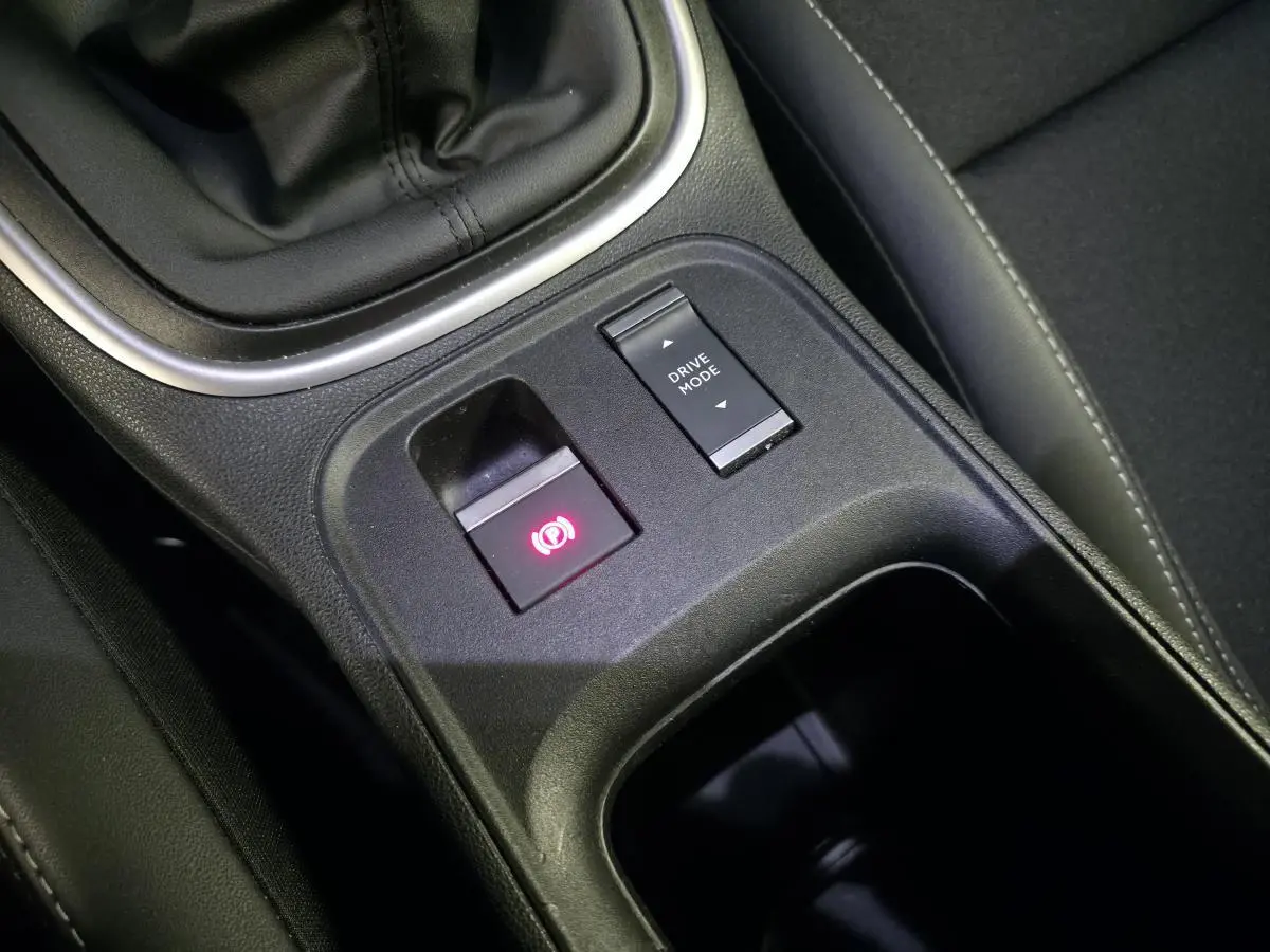 Gros plan sur la console centrale noire du Jeep Avenger 2025 montrant frein de stationnement électrique et bouton Drive Mode.