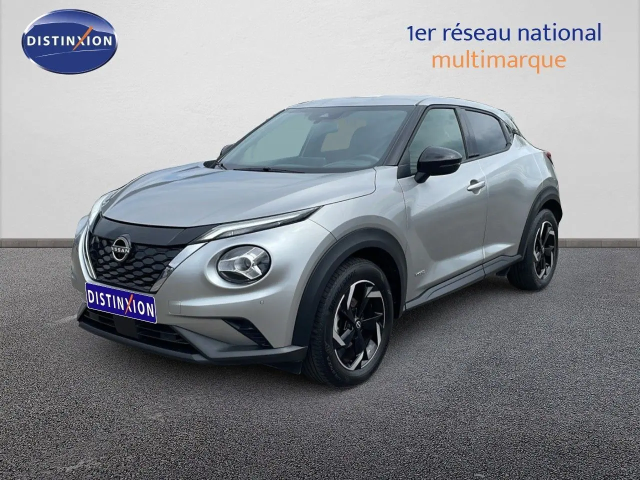 Nissan Juke Hybrid gris perle métal vu en 3/4 avant droit, avec jantes noires et détails noirs contrastants.