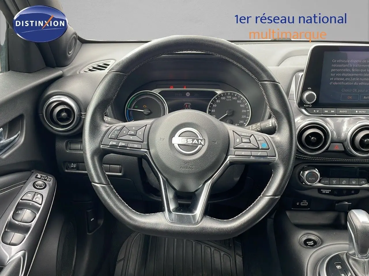 Vue centrée sur le volant noir du Nissan Juke Hybrid 2023 avec tableau de bord et écran tactile visible.