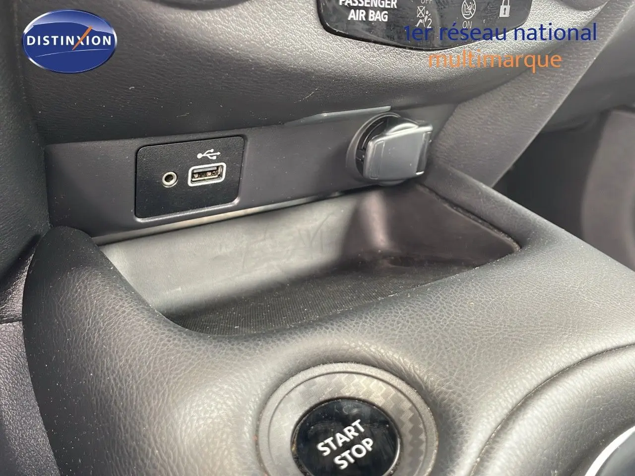 Gros plan sur la console centrale d'un Nissan Juke Hybrid gris perle, montrant le bouton start/stop et une prise USB.