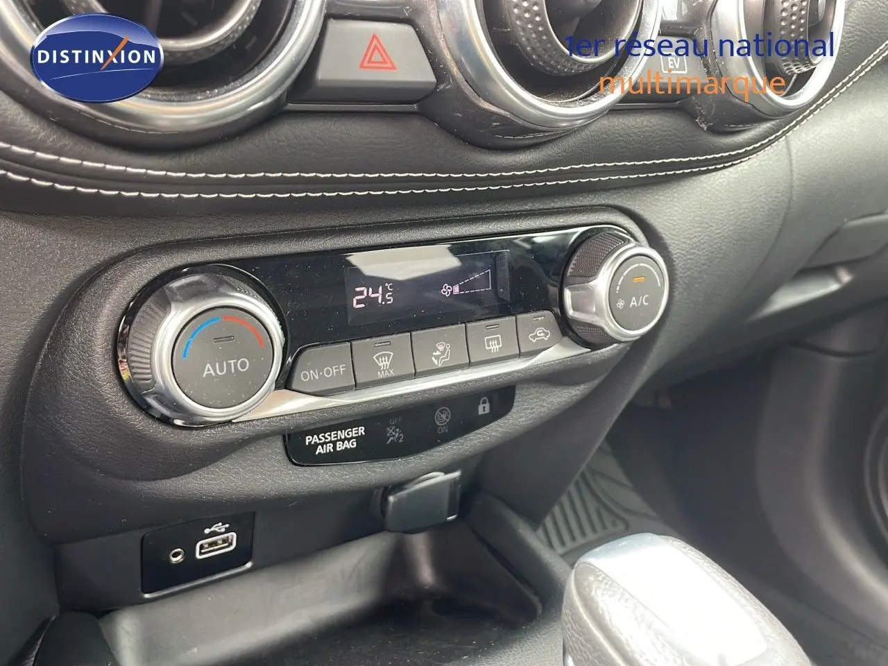 Détail de la console centrale du Nissan Juke Hybrid 2023 gris perle, montrant la climatisation automatique et la boîte automatique.