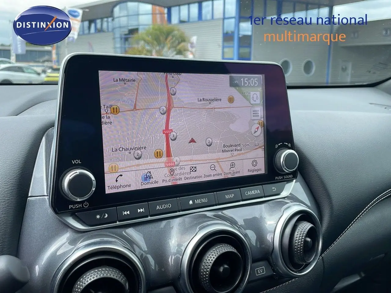 Tableau de bord du Nissan Juke Hybrid 2023 en gris perle, avec écran tactile affichant la navigation et aérateurs ronds métallisés.