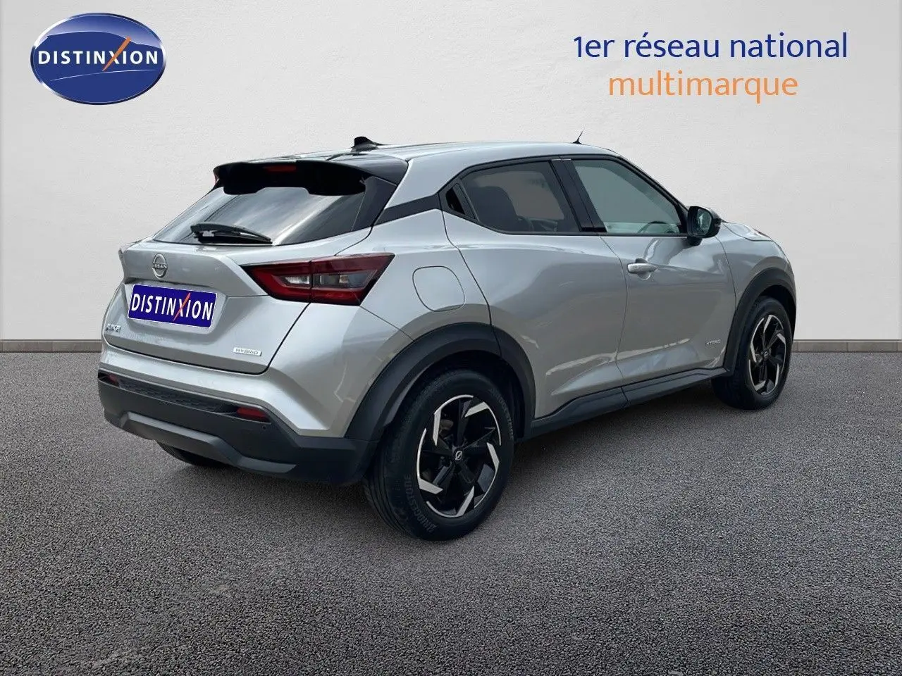 Nissan Juke Hybrid gris perle métal vu en 3/4 arrière droit, soulignant ses jantes noires et son design compact.