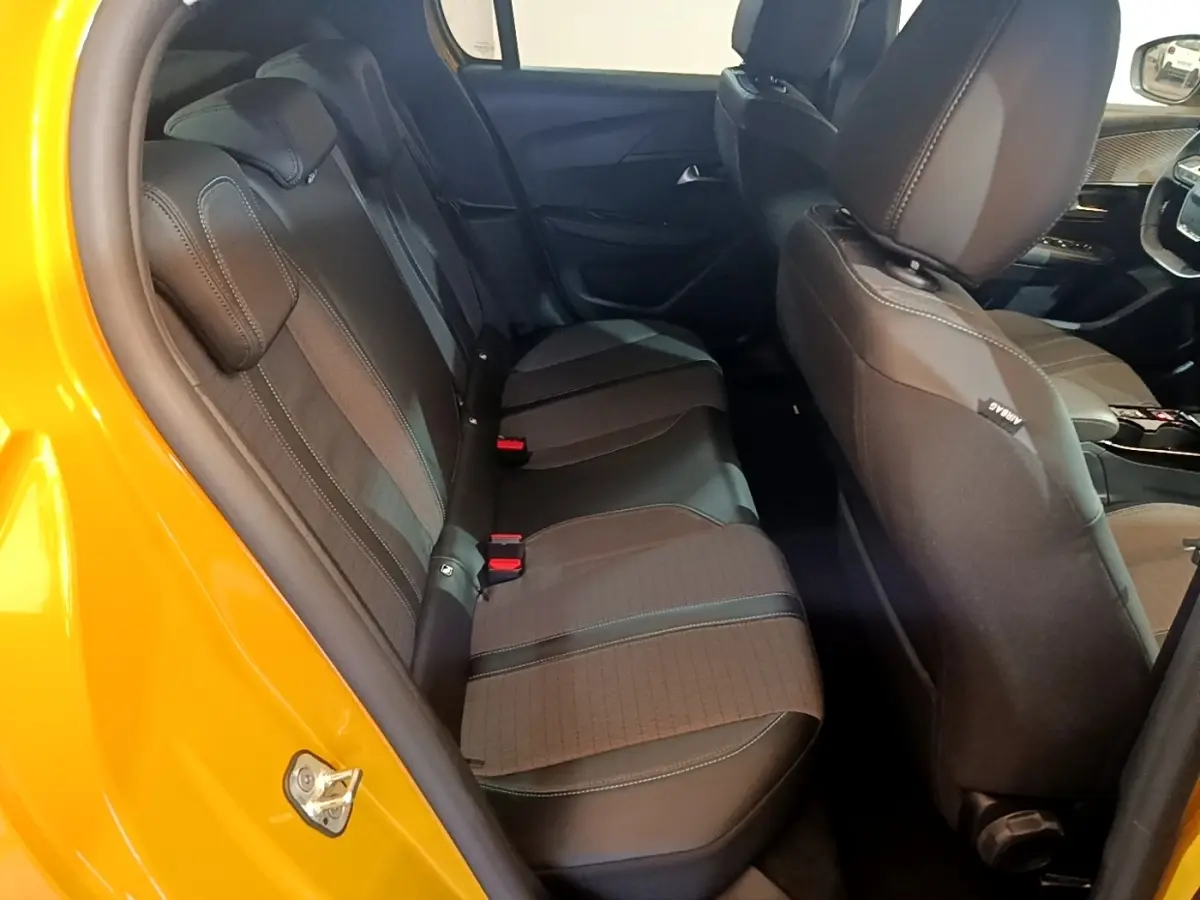 Vue intérieure côté gauche montrant la banquette arrière noire et le siège avant d'une Peugeot 208 jaune 2023.