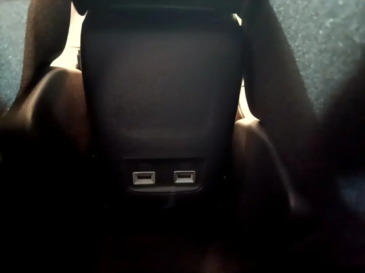 Gros plan sur les ports USB arrière noirs du siège central dans l’habitacle d’une Peugeot 208 jaune 2023.