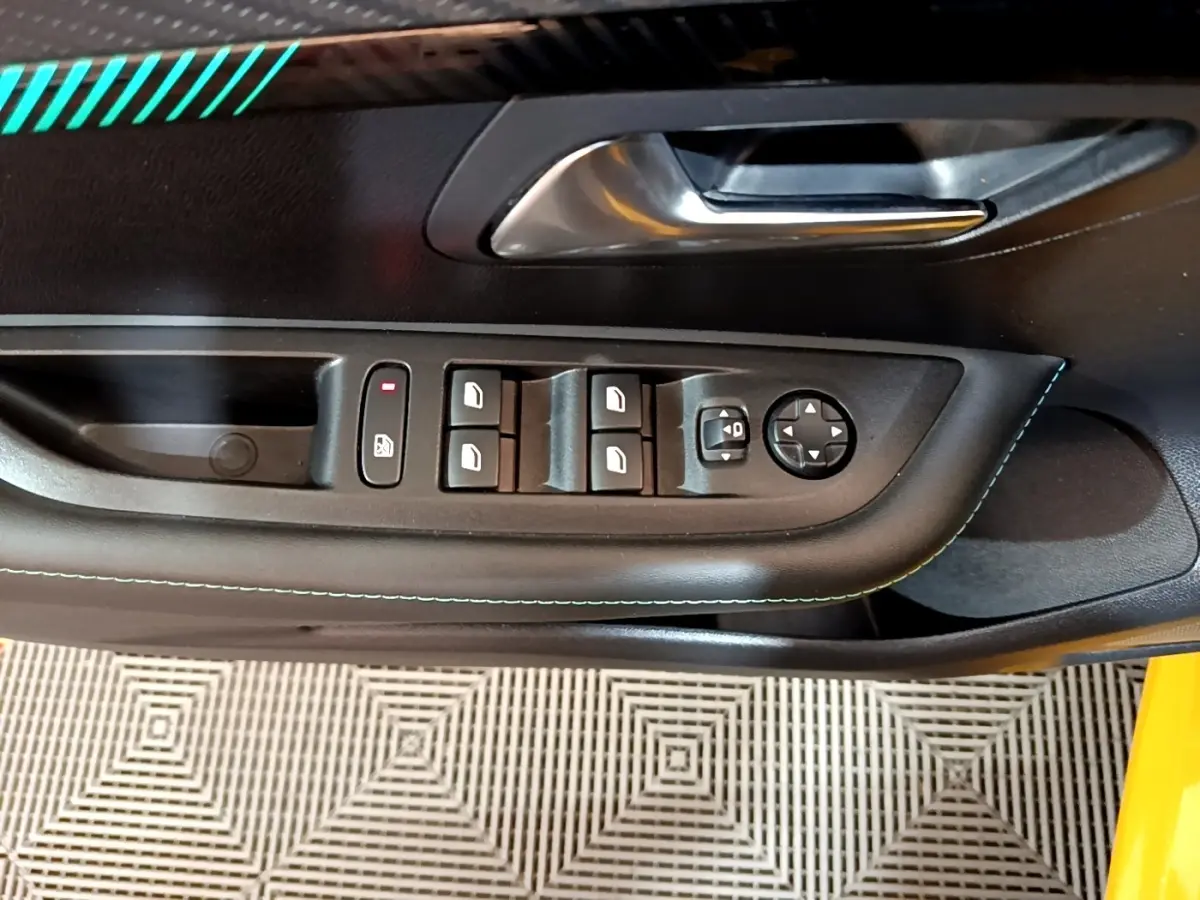 Gros plan sur la porte côté conducteur de la Peugeot 208 jaune, montrant les commandes électriques des vitres et rétroviseurs.