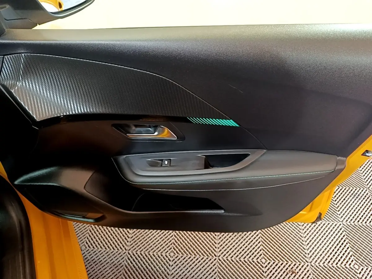 Vue intérieure de la porte avant gauche noire avec surpiqûres bleues sur Peugeot 208 jaune 2023.