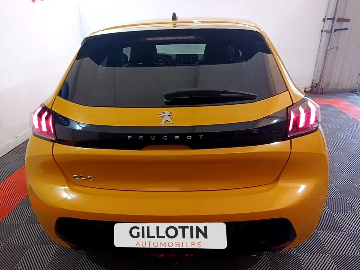 Vue arrière d'une Peugeot 208 jaune 2023 avec feux LED caractéristiques et bande noire brillante sur le hayon.